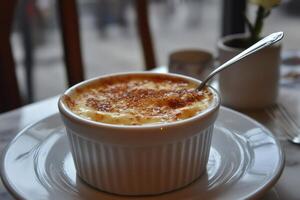 Delicious creme brulee served in white ramekin on restaurant table photo
