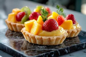 Delicious fruit tarts with mango, kiwi and strawberry topping a creamy filling photo