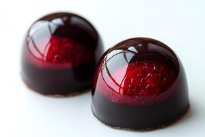 Two bonbons with raspberry filling covered with dark chocolate glaze are waiting to be eaten photo