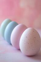 Four pastel easter eggs creating a diagonal line on pink background photo