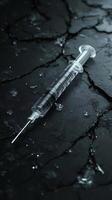 Syringe laying on cracked dark surface with ice shards photo