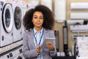 Female retail employee using a digital tablet in an appliance store. Smiling sales associate assisting customers with home electronic purchases. photo
