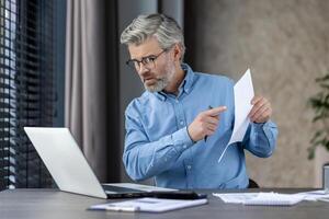 Mature businessman explaining documents while on a call, working remotely from a home office environment. photo
