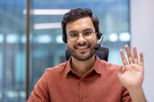 Customer service professional with headset waving hand and smiling in modern office. Image captures friendly communication, professionalism, positive attitude, technology, and customer support. photo