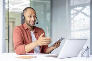 Man with headset and laptop inside office at workplace. Support worker consulting and helping customers consumers remotely. photo