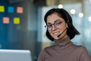 Confident customer service representative with headset and glasses smiling at camera. Engaged in conversation at work with positive demeanor. Represents communication, professionalism, and support photo