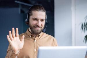 A man communicating in a call on a laptop, wearing a headset in a modern setting. photo