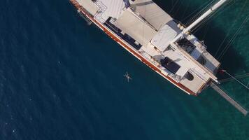 Aerial. a yacht is anchored in a bay, and a person is floating in the water. video