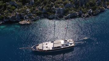 Aerial. Large boat is floating in the ocean with a small boat tied to it video
