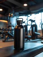 A black water bottle sitting on a table in a gym photo