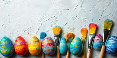 Colorful painted eggs and brushes arranged on a textured surface during an art activity photo