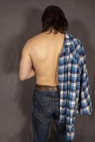 Muscular man back with shirt stay on a grey background. photo