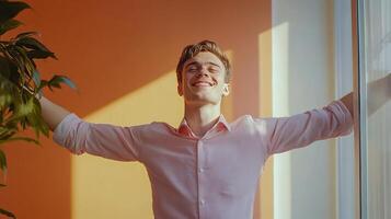 A man is standing by a window with his arms outstretched photo