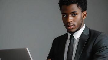 A man in a suit and tie is looking at a laptop photo