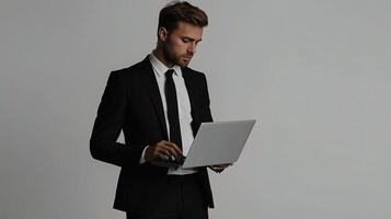 A man in a suit and tie is holding a laptop photo
