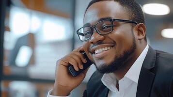 A smiling black man in glasses talking on a cell phone photo