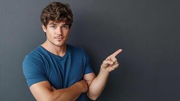 Handsome young man pointing finger on gray background photo