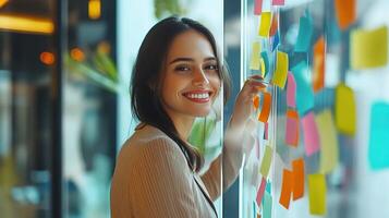 A woman smiling while looking at a wall covered with sticky notes photo