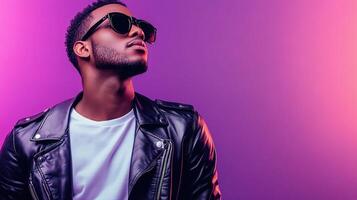 Portrait of a young man in sunglasses and leather jacket on purple background photo