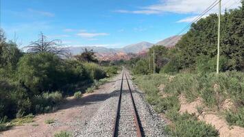 Panoramic view of the railroad tracks of the Solar Train in the Quebrada region of Jujuy, Argentina, surrounded by a mountainous landscape and vegetation. video