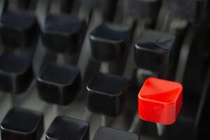 A red typing key stands out among black keys on a retro typewriter creating a striking visual contrast photo