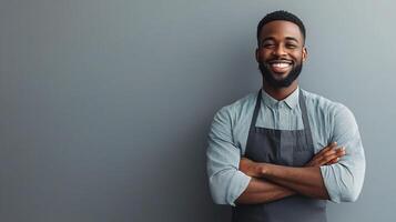 A smiling black man in an apron standing with his arms crossed photo