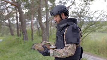 Man in a special suit works with a detector and found an explosive device. A man tries to neutralize an anti-tank mine. video