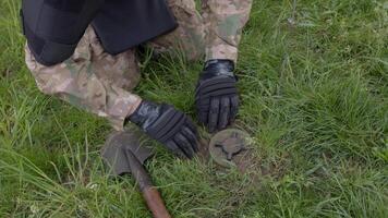 A man in a military uniform and a bulletproof vest works in the forest to demine the territory. A man defuses an anti-personnel mine. video