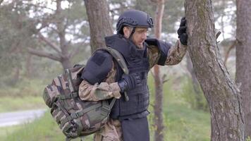 Soldier in uniforms and tactical vest works in the forest and prepares for action at a temporary forest base. A man does in the work of demining the territory video