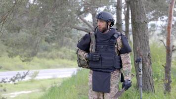 Young soldier in uniforms and tactical vest works in the forest and prepares for action at a temporary forest base. A man does in the work of demining the territory. video