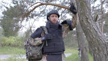 Young soldier in uniforms and tactical vest works in the forest and prepares for action at a temporary forest base. Man does in the work of demining the territory video
