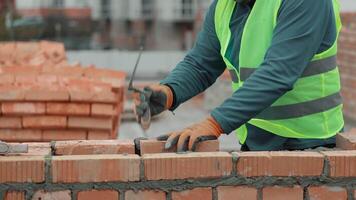 Construction worker laying bricks on a wall, Close-up of a construction worker building a brick wall with a trowel on a construction site. video