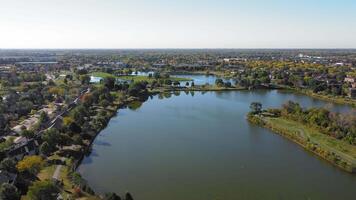 Aerial view of a serene lake and suburban area, Scenic aerial view of a large lake surrounded by green parks, trees, and suburban homes. video