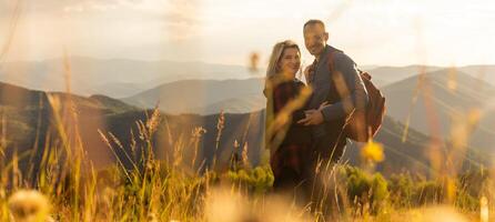 Happy traveler young couple resting in the mountains at sunset in spring or summer season. photo