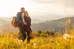 Happy traveler young couple resting in the mountains at sunset in spring or summer season. photo