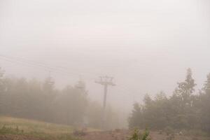 Old abandoned ski lift in mountain. Foggy mood. photo