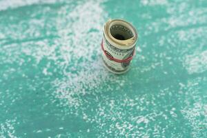 100 dollar bills twisted into tube and tied with an elastic band. white background, copy space for your text photo