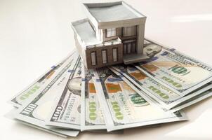 House standing on a pile of dollar bills. Investment, real estate and property concept photo
