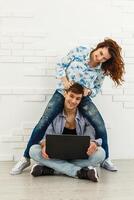 Couple Use Laptop Computer, while Sitting on the Living Floor room of their Apartment. Boyfriend and Girlfriend Talk, Shop on Internet, Choose Product to Order Online, Watch Streaming Service. photo