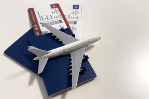 Toy airplane and passport with tickets on gray background, top view photo