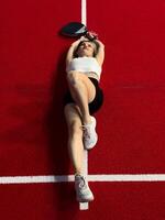 woman in white clothing lying with racket lying on paddle tennis court with racket photo