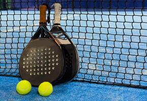 Paddle racket with a ball ready to play the fastest growing sport in recent years worldwide. Padel court in summer, the perfect time to practice this sporting discipline and release stress. photo