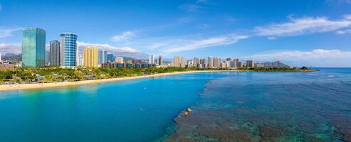 Aerial view of Waikiki Beach in Honolulu, Hawaii, with turquoise waters, coral reefs, high rise buildings, and Diamond Head crater in the background. photo