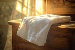 Soft white towel on wooden dresser bathed in warm sunlight photo