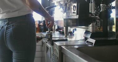 Young woman barista presses the ground coffee, preparing it for the coffee machine. The processes of brewing coffee in a cafe in detail, close-up, the woman's face is not visible video