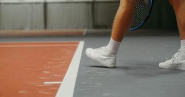 Close-up of the legs of a young male tennis player in white sneakers, bouncing while serving the ball with a racket video