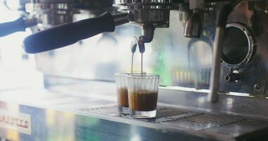 A professional coffee machine pours two cups of coffee at once, thin streams gradually fill the glasses. Close-up, no people in the frame video