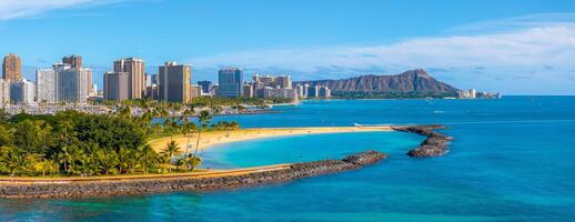 Aerial view of Waikiki Beach in Honolulu, Hawaii, with turquoise waters, golden sands, palm trees, modern skyline, and Diamond Head crater in the background. photo
