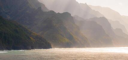 The Napali Coast on Kauai Island, Hawaii, features rugged cliffs, lush greenery, and jagged peaks descending into the ocean under soft sunlight. photo