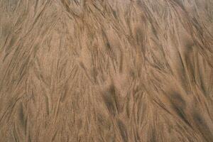 Golden brown sand displays intricate, vein like patterns created by water flow, forming an abstract and textured natural design. photo